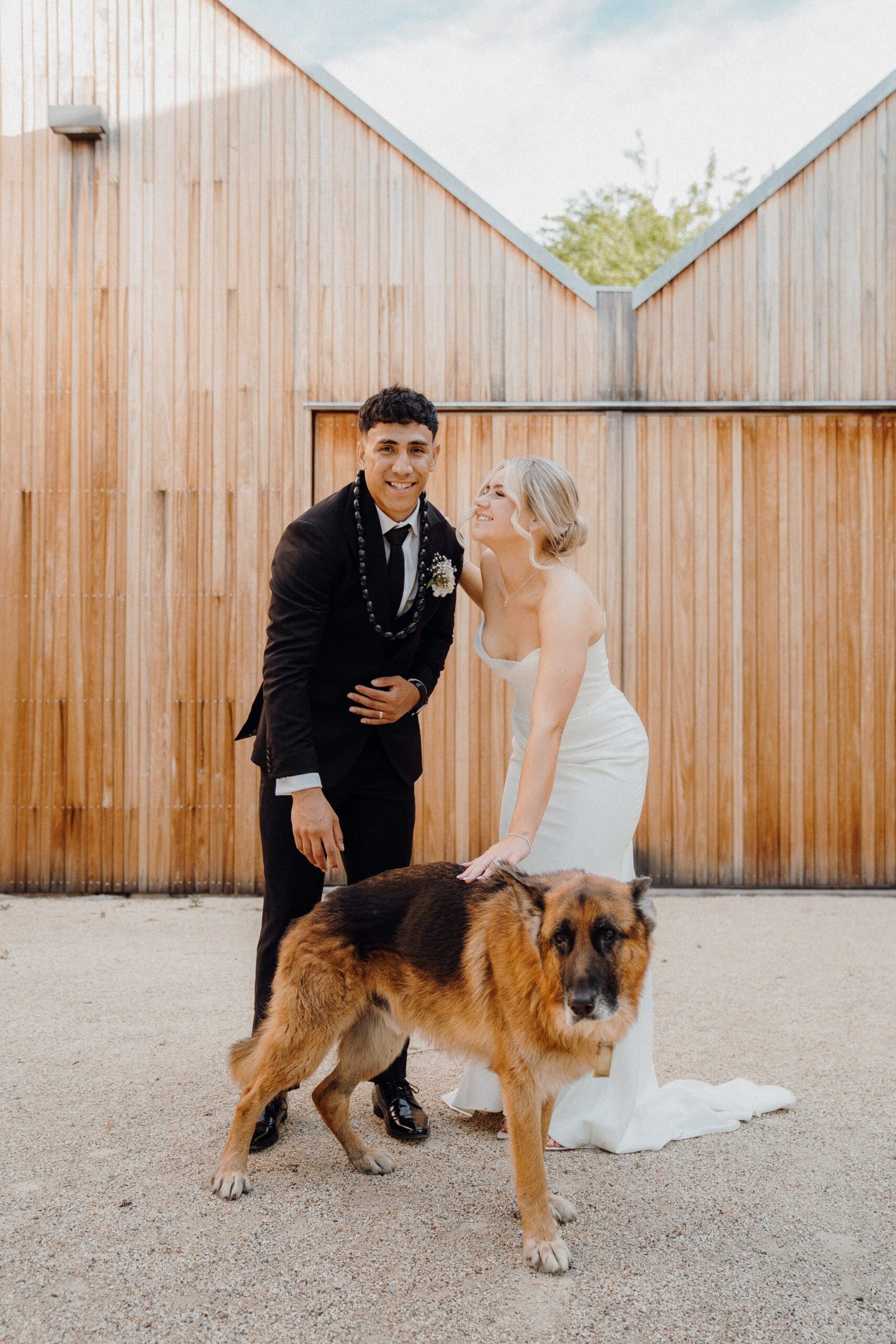 A couple with their German shepherd against the timber wall