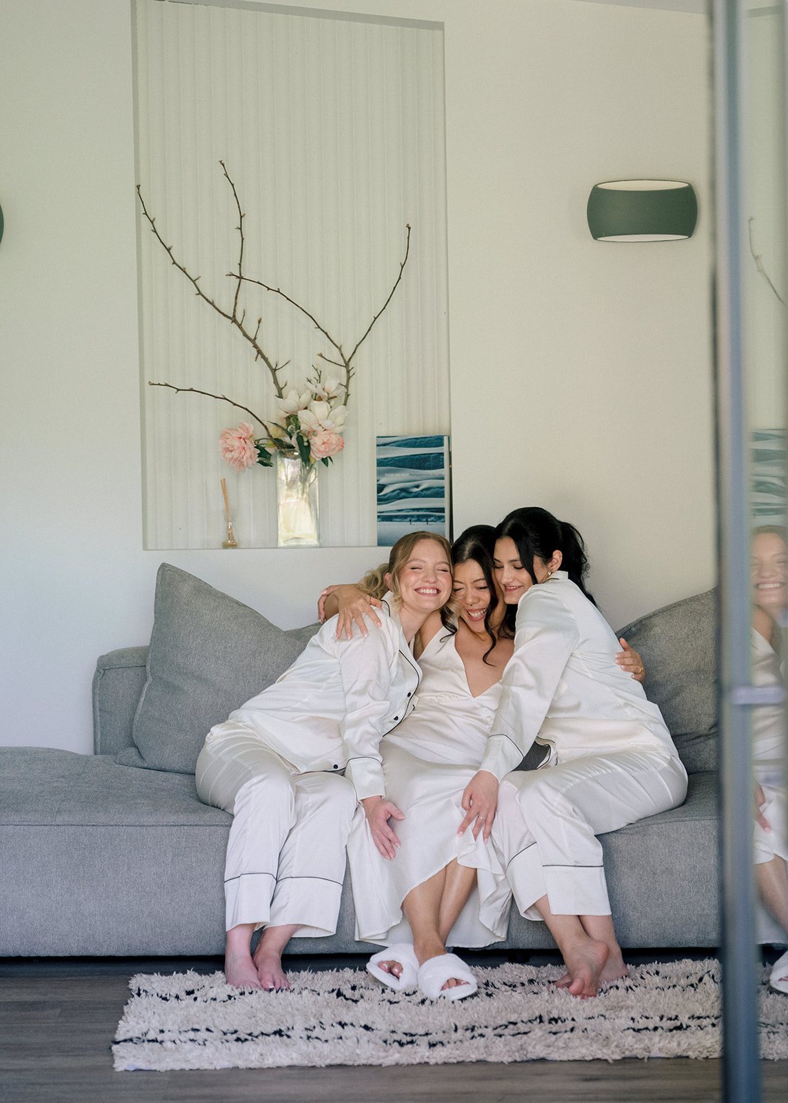 A bride and bridesmaids in robes on the couch, getting ready