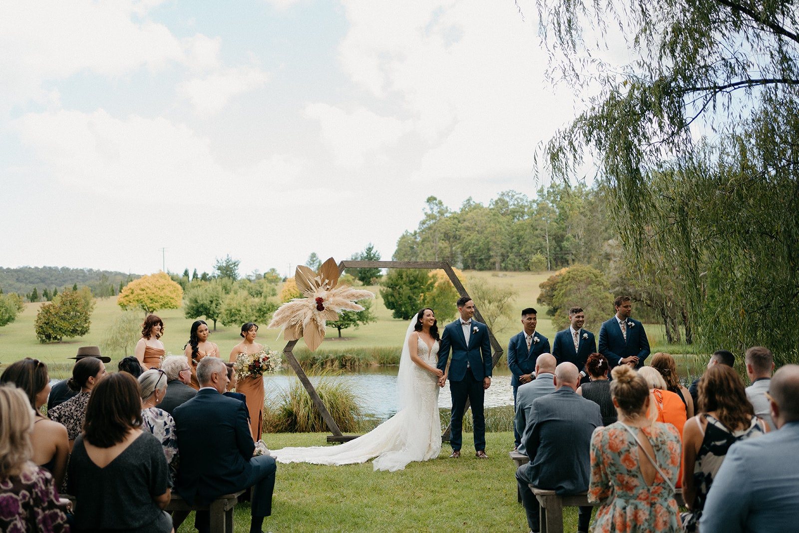 A lakeside ceremony under the willows, guests seated